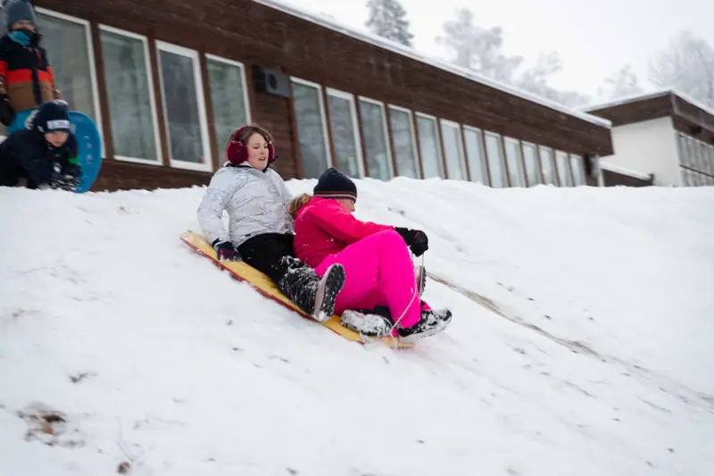 To jenter aker ned en bakke på samme akebrett