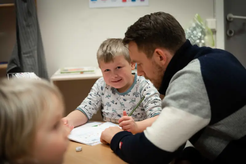 Lærer og en smilende elev jobber sammen ved et bord